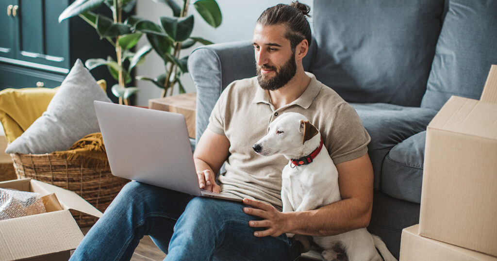 man sitting with dog looking for pet shipping online
