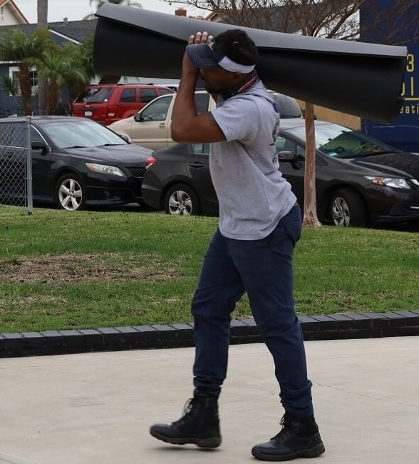 Delivery crew member carrying wrapped furniture