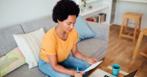 Woman looking paper while working on laptop