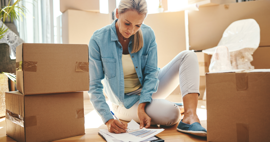 Woman going over paperwork on the floor near moving boxes